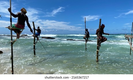 Koggala, Sri Lanka – April 30, 2022: Stilt Fishermen Fishing On A Stick On The Coast Of Koggala, Sri Lanka. 