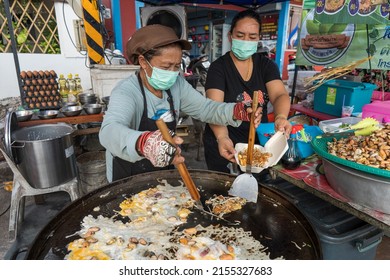 Koh Phangan, Thailand - february 12, 2022 : Thai street vendor woman prepares and sells food on the traditional street market at island Koh Phangan, Thailand. Cooking fried mussel omelette