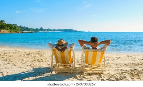 Koh Samet Island Rayong Thailand, the white tropical beach of Samed Island with a turqouse colored ocean, a couple of men and woman relaxing in a beach chair looking out over the ocean with arms up - Powered by Shutterstock