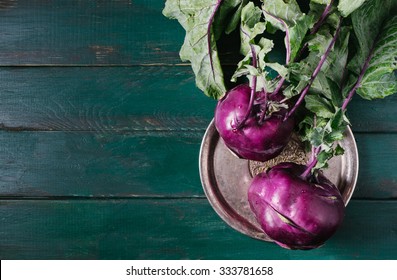 Kohlrabi cabbage with green leaves on a metal plate on wooden background of old vintage boards top view - Powered by Shutterstock