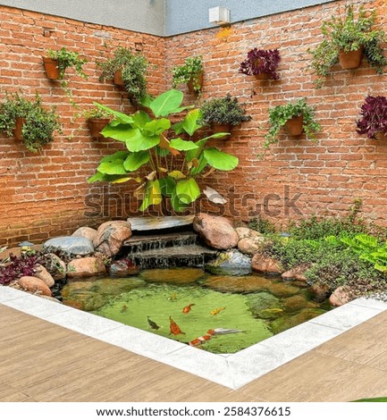 Koi pond with rustic brick wall. Plants decorating the pond. Waterfall, water fountain, rocks. Lake in the city.