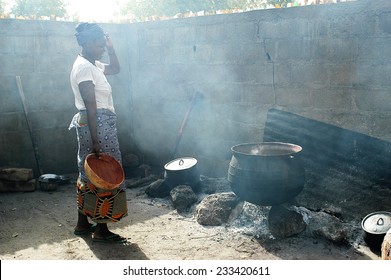 KOKEMNOURE, BURKINA FASO - FEBRUARY 23: Reserved large pot for cooking local beer in Burkina Faso, a woman lights firewood, february 23, 2007