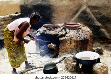 KOKEMNOURE, BURKINA FASO - FEBRUARY 23: Reserved Large Pot For Cooking Local Beer In Burkina Faso, A Woman Lights Firewood, February 23, 2007