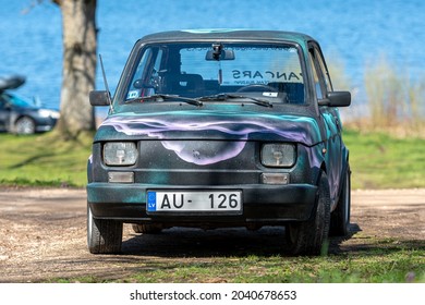 Koknese, Latvia - May 01, 2021: colorful oldtimer PanCars rental car Fiat 126 parked on the side of a country road