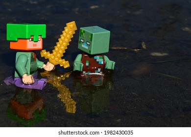 KOLAROVO, SK - MAY 28, 2021: Minecraft LEGO Figure Of Alex With Golden Sword And Tortoise Shell Helmet Attacking Suprised Drowned Zombie Mob In Shallow Waters. Daylight Spring Sunshine.