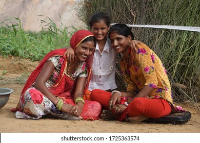 Kolayat, Bikaner, Rajasthan / India, September 03,2017: Three beautiful  Rajasthani girls laughing and talking sitting outside the hut of a farm in Kolayat village