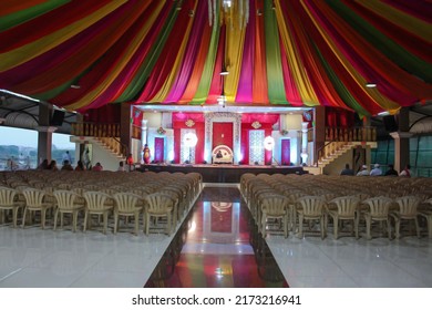 Kolhapur,India- January 28th 2019;Stock Photo Of Beautifully Decorated Wedding Hall's Roof Top Or Tent With Colorful Curtains, Stage Decorated With Red Rose And Bright Lights. Chairs In Front Of Stage