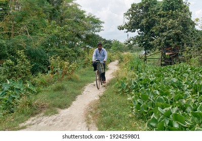 Kolkata, 10-2-2020: Daily life of people living near East Kolkata Wetlands. A middle aged person is seen riding bicycle through narrow dirt road, amidst lush green surroundings.