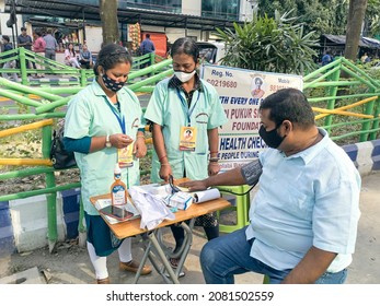 Kolkata, 11-01-2021: Health Technicians Checking Blood Pressure Level Of A Person, Using A Digital BP Machine At A Roadside Free Health Checkup Camp Organised By An NGO, At Sector V, Saltlake.