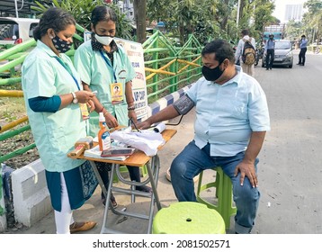 Kolkata, 11-01-2021: Health Technicians Checking Blood Pressure Level Of A Person, Using A Digital BP Machine At A Roadside Free Health Checkup Camp Organised By An NGO, At Sector V, Saltlake.