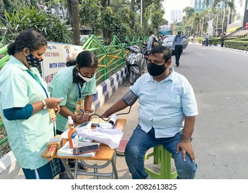 Kolkata, 11-01-2021: Health Technicians Checking Blood Pressure Level Of A Person, Using A Digital BP Machine At A Roadside Free Health Checkup Camp Organised By An NGO, At Sector V, Saltlake.