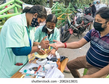 Kolkata, 11-01-2021: Health Technicians Checking Blood Sugar Level Of A Person, Using A Digital Glucometer At A Roadside Free Health Checkup Camp Organised By An NGO, At Sector V, Saltlake.