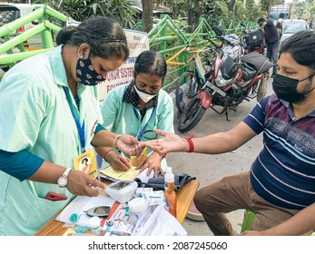 Kolkata, 11-01-2021: Health Technicians Checking Blood Sugar Level Of A Person, Using A Digital Glucometer At A Roadside Free Health Checkup Camp Organised By An NGO, At Sector V, Saltlake.