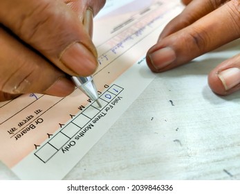 Kolkata, India dated 09.09.2021. Man is writing cheque and date with pen.