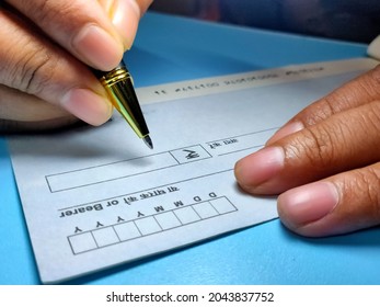 Kolkata, India, dated 19.09.2021. Man is writing cheque and date with pen.