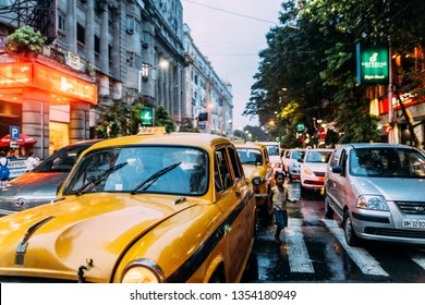KOLKATA, INDIA. JUL 22, 2017: Yellow taxi with traffic jam on the road with a boy walking on in the evening with lights at Kolkata, India.