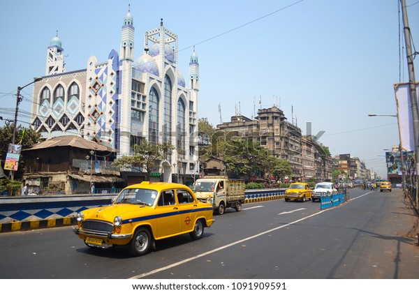 Kolkata, India - March, 2014: Classic yellow taxi\
cab ambassador on the street in a front of mosque in Calcutta.\
Indian traffic road
