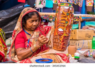 KOLKATA, INDIA - NOVEMBER 28: An Indian elderly craftswoman paints on colorful earthen vase for sale during the annual State Handicrafts Expo 2015 on November 28, 2015 in Kolkata, West Bengal, India.