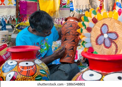 Kolkata, West Bengal, India - 31st December 2018 : Young Bengali artist man painting colors on terracotta pots, works of handicraft, for sale during Handicraft Fair in Kolkata.