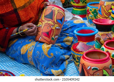 Kolkata, West Bengal, India - 31st December 2018 : Female Indian artist painting colorful terracotta pots, works of handicraft, for sale during Handicraft Fair in Kolkata.