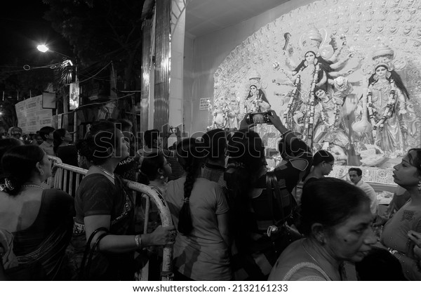 Kolkata, West Bengal, India - 8th October, 2019 :\
Hindu devotees visiting decorated Durga Puja pandal at night with\
idol of Goddess Durga inside. Biggest festival of Hinduism. Black\
and white.