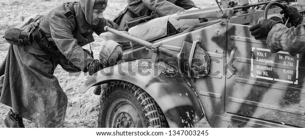 KOLOBRZEG, WEST POMERANIAN / POLAND - 2019:\
Reconstruction of battle for Kolobrzeg - German soldier pushing a\
military off-road car on a sea\
beach\
