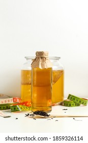 Kombucha Drink In A Glass Bottle, A Can Of Kombucha Mushroom, Tea Leaves On A Wooden Spoon And Measuring Tape On A Light Background