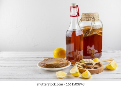 Kombucha superfood pro biotic tea fungus beverage in glass bottle and jar with lemon, ginger, tea on white background. copy space