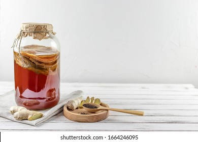 Kombucha superfood pro biotic tea fungus beverage in glass bottle and jar with ginger, tea on white background. copy space