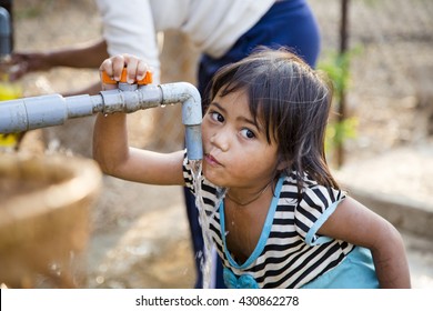Kon Tum, Vietnam - Mar 29, 2016: A little girl drink water from outdoor tap which water supplied by drilling well in Central Highland of Vietnam. Fresh water is problem in underdevelopment region