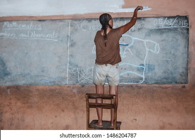 Kongo Village / Ghana - 03.14.2015: A Woman With Afro Braids Is Painting A Wall Of A Local Elementary School In Ghana, Africa