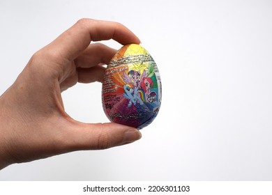 Kongsvinger, Norway 25 September 2022: Hand Holding My Little Pony Chocolate Egg With Surprise Gift Toy Inside Isolated On White Background