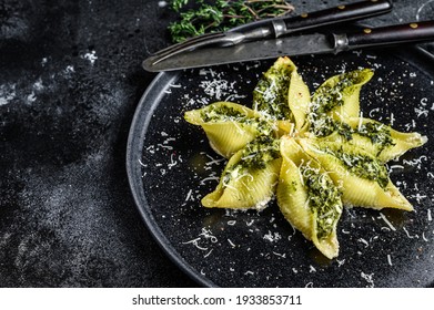 Konkiloni Italian Jumbo shells pasta Conchiglioni stuffed with beef meat and spinach on a plate. Black background. Top view. Copy space.