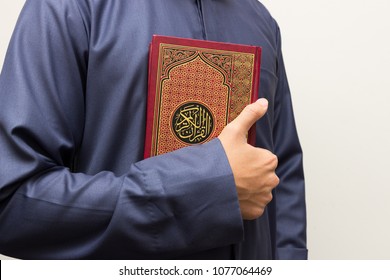 Koran in hand. Arabic word translation : The Holy Al Quran (holy book of Muslims) - public item of all muslims
