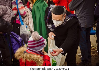 Korczowa, Poland 5.03.2022 - a Jew offers sweets to a child fleeing the war from Ukraine                          