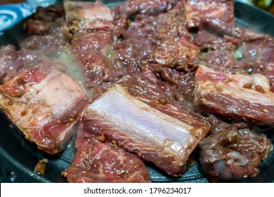 Korean Barbequed Beef Short Ribs (Kalbi or Galbi) sizzling on a hot plate with rising smoke. The cut is also called flanken. Catering Concept.