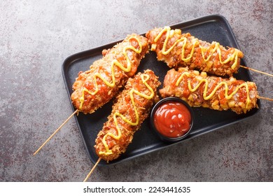 Korean corn dogs are hot dogs, cheese, French fries fried in a batter on a stick and dressed with sugar, ketchup, mustard closeup on the plate on the table. Horizontal top view from above
 - Powered by Shutterstock