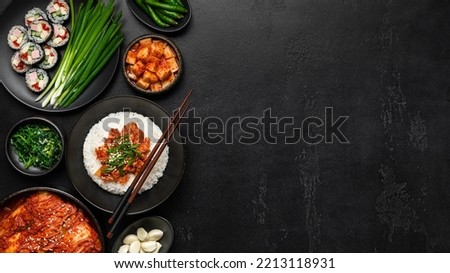 Korean food on a black background. Rice, kimchi, kimbap, pickled radish, vegetables and herbs, flat lay, banner, copy space