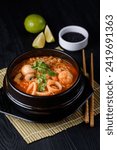 Korean food. seafood soup, salmon soup, eel soup, shrimp. on a black wooden background.