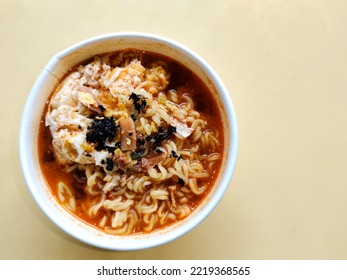 Korean Food Tteok Ramyeon (Rice Cake Ramen) In White Paper Bowl. Yellow Table Surface Background. Negative Space 