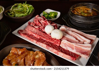 Korean Grilled BBQ combo with pork belly, wagyu and marinated chicken set on the traditional grill table, with lettuce, dipping sauce, soup and pickle dishes