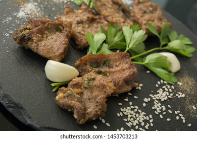Korean grilled meat, bulgogi, barbecue meat with scattered spices, sesame on dark slate closeup - Shutterstock ID 1453703213
