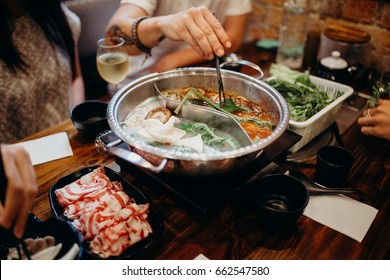 Korean hot pot meal. Hands taking food with chopsticks.