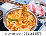 Korean Instant Tteokbokki with Ramen Noodles and Blurred Beef Background