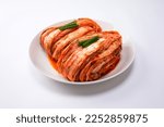 Korean kimchi. Korean traditional cabbage kimchi on a white plate. White background, closeup.