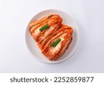 Korean kimchi. Korean traditional cabbage kimchi on a white plate viewed from above. White background, closeup.