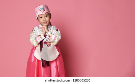 Korean little baby girl in traditional silk dress for new year celebration on pink background with hands in pray sign - Powered by Shutterstock