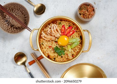 Korean spicy instant noodle,ramyeon or Ramyun, with egg yolk, kimchi inside a traditional korean noodle pot.Serving a Korean style from top view.white background