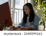 Korean student girl wearing glasses using desktop computer for online learning, working or studying from home. Female freelance journalist typing on keyboard writing for magazines and newspapers