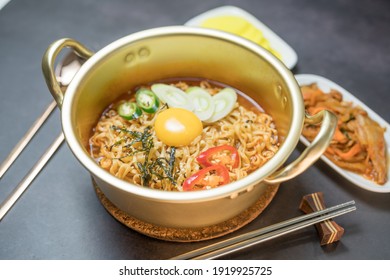 Korean style instant noodle, Ramyeon with egg yolk, chilli, kimchi vegetables pickled and radish pickles in a traditional korean noodle pot. - Shutterstock ID 1919925725